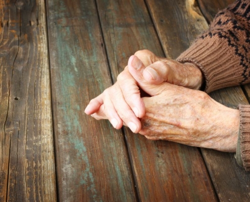 Older hands on a wooden table