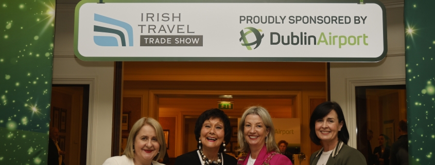 Four ladies stand cutting a ribbon to mark the opening of the Irish Travel Trade Show Dublin with a banner behind announcing Dublin Airport as sponsors of the event.