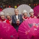 4 girls in traditional chinese clothes while the lord mayor of Dublin poses with them, all have smiles on their faces and pink umbrellas are in the foreground and background.