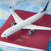 A toy plane sitting on top of a red passport on a table covered by a map.