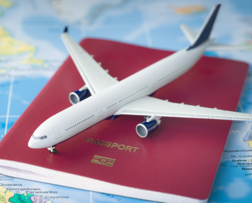 A toy plane sitting on top of a red passport on a table covered by a map.
