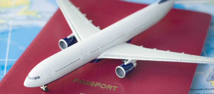 A toy plane sitting on top of a red passport on a table covered by a map.