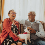 732×594-older couple with dog An older couple sitting on a couch with a dog.