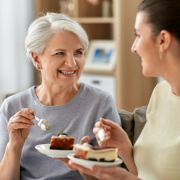 An old woman and a young woman sharing a cake in friendship
