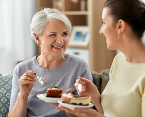An old woman and a young woman sharing a cake in friendship