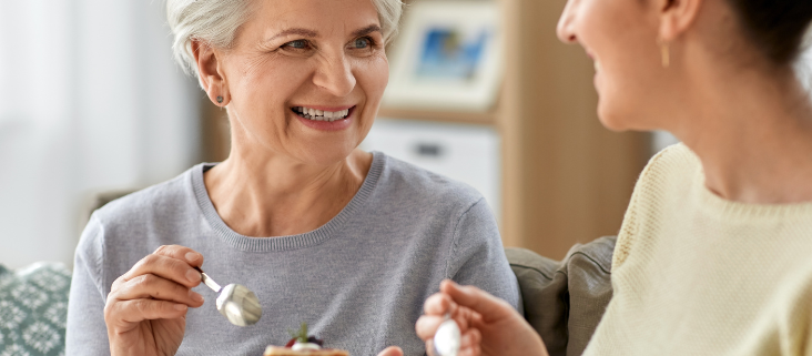 An old woman and a young woman sharing a cake in friendship